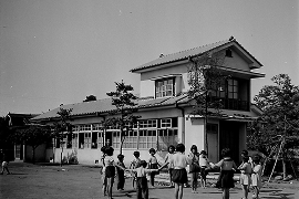 増築した本館と、園庭に集まるこどもたち（白黒写真）
